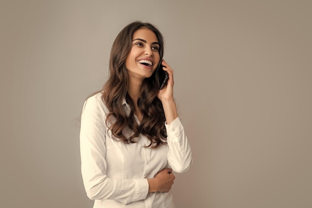 Femme souriante avec smartphone debout sur fond gris