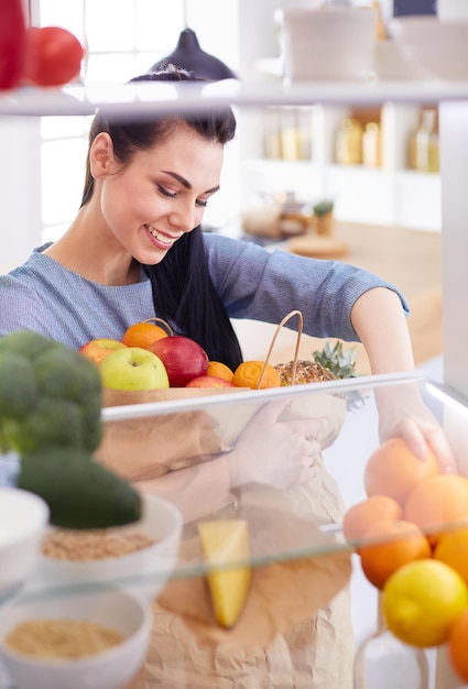 Femme souriante sortant un fruit frais du réfrigérateur concept d'aliments sains