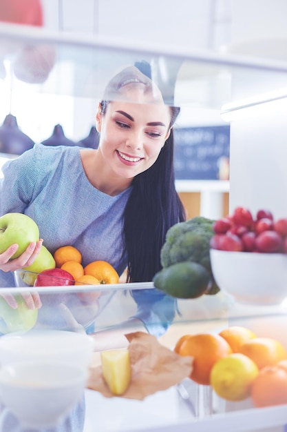 Femme souriante sortant un fruit frais du réfrigérateur concept d'aliments sains