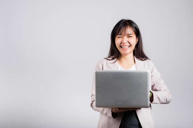 Femme souriante souriante confiante tenant à l'aide d'un ordinateur portable et d'un clavier de saisie pour envoyer des e-mails ou discuter en ligne