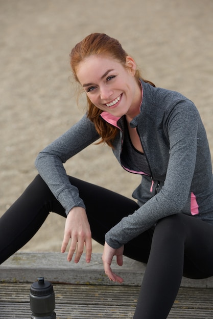 Femme souriante de sport assis à l&#39;extérieur