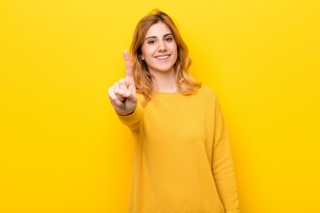 Photo femme souriante et sympathique, montrant le numéro un ou le premier avec la main vers l'avant, compte à rebours