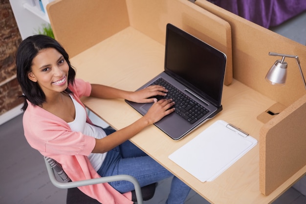 Femme souriante, tapant sur son ordinateur