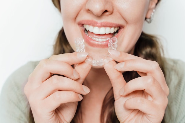 Une femme souriante tenant un aligneur de dents clair