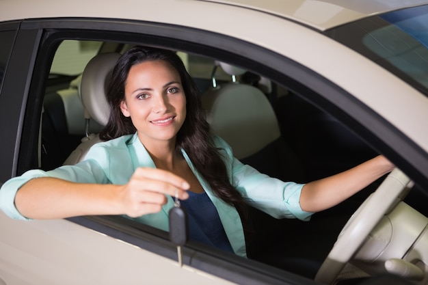 Femme souriante tenant la clé de voiture