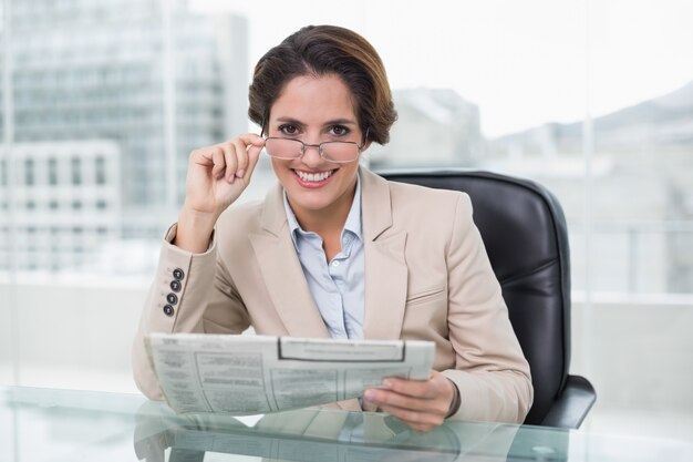 Femme souriante tenant un journal à son bureau