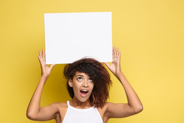 Photo une femme souriante tenant une pancarte debout sur un fond jaune