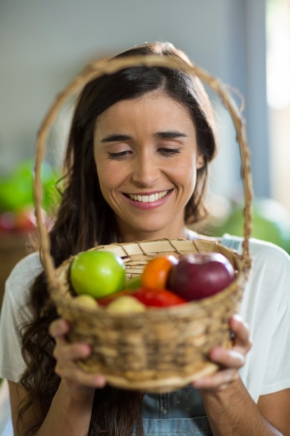 Femme souriante tenant un panier de fruits