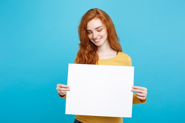 Une femme souriante tenant un papier blanc sur un fond bleu