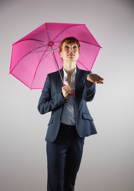 Femme souriante tenant un parapluie rose