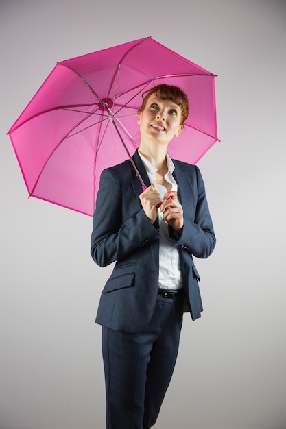 Femme souriante tenant un parapluie rose