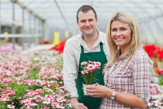 Femme souriante tenant un pot de fleur avec un employé