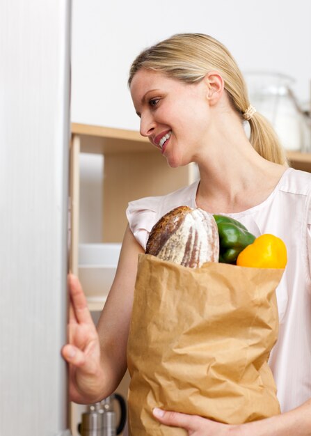 Femme souriante tenant un sac d&#39;épicerie