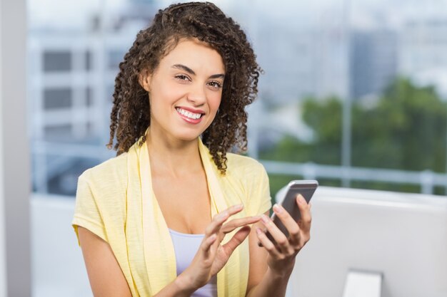 Femme souriante tenant son téléphone