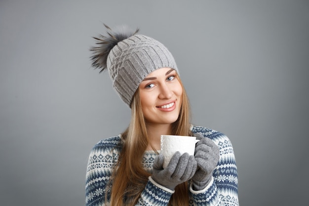 Femme souriante tenant une tasse avec une boisson chaude