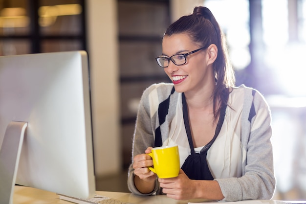 Femme souriante tenant une tasse de café au bureau