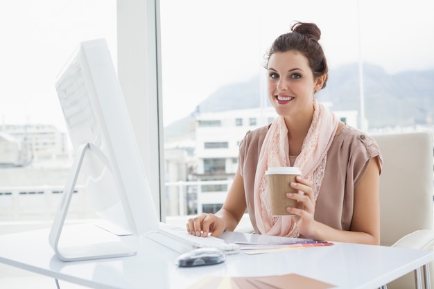 Femme souriante tenant une tasse de café en papier