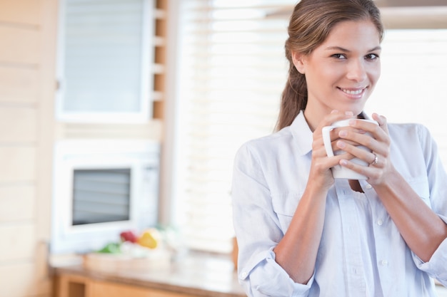 Femme souriante tenant une tasse de café