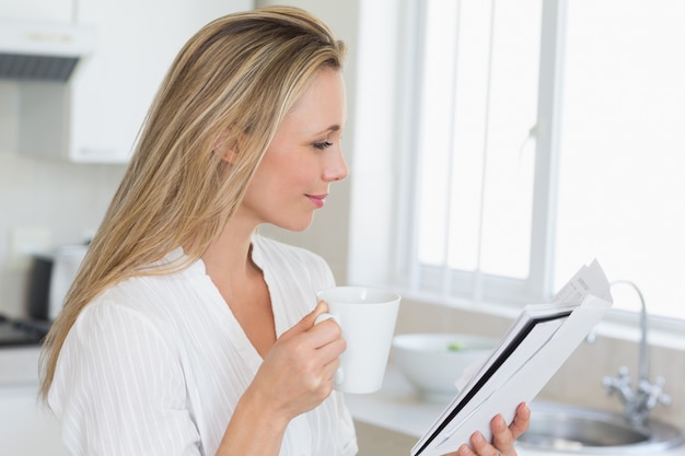 Femme souriante tenant la tasse et le journal