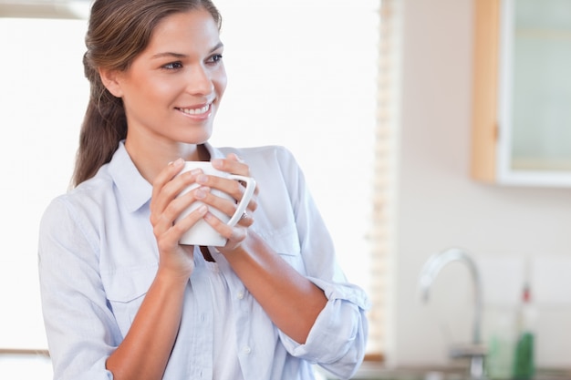 Femme souriante tenant une tasse de thé