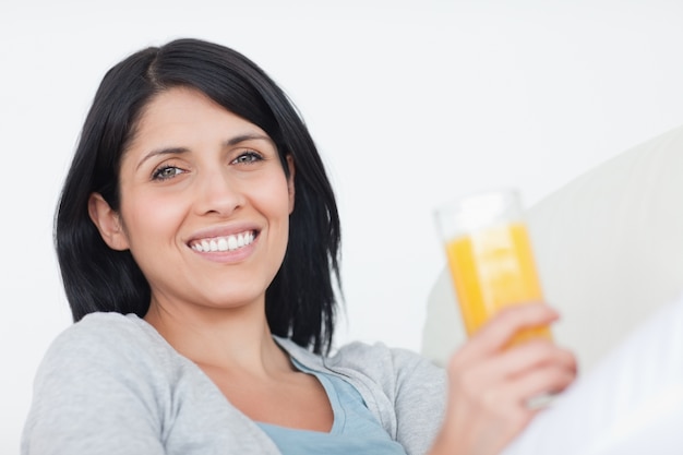 Femme souriante tenant un verre de jus