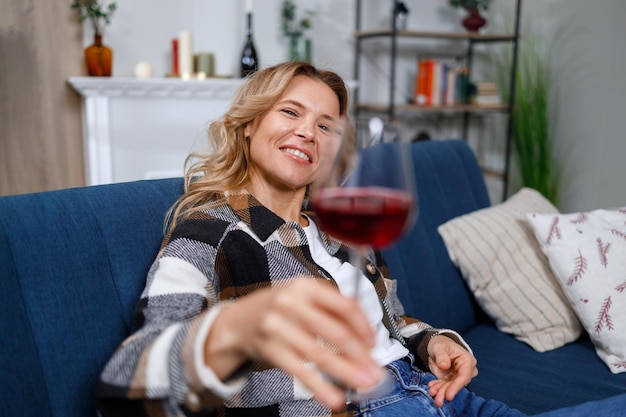 Une femme souriante tenant un verre de vin à la maison