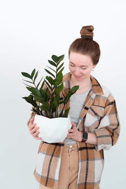 Femme souriante tenant des zamioculcas en pot blanc dans les mains isolés sur fond blanc