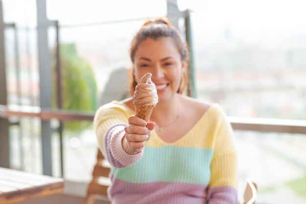 Photo une femme souriante tient une délicieuse crème glacée dans des couleurs pastel en gros plan