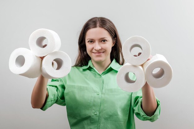 Une femme souriante tient trois rouleaux de papier toilette dans chaque main