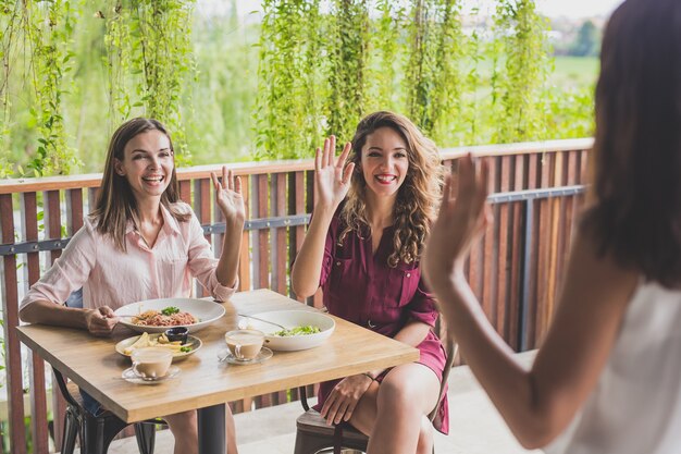 femme souriante tout en agitant les mains à leurs amis