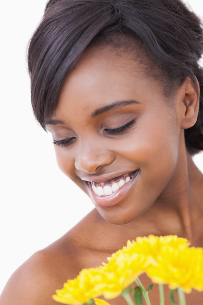 Femme souriante tout en tenant des fleurs jaunes