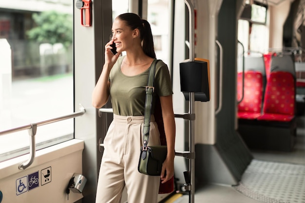 Une femme souriante en train de discuter dans un tram qui fait un appel téléphonique.