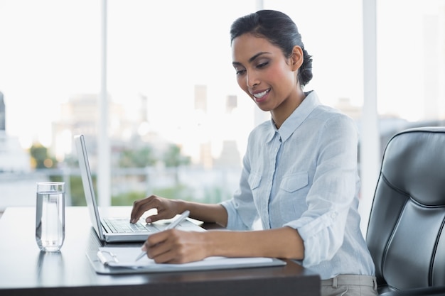 Femme souriante de travail travaillant assis à son bureau