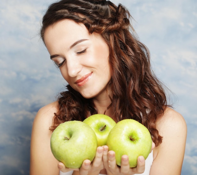 Femme souriante avec trois pommes vertes