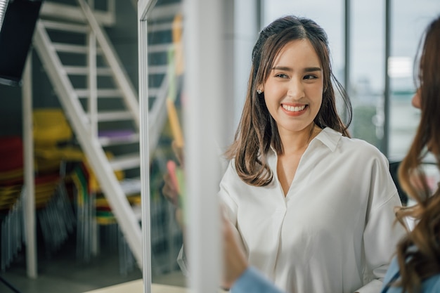 femme souriante et utilisant des notes post-it à partager sur le projet