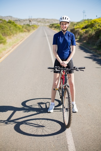 Femme souriante avec vélo sur l&#39;autoroute