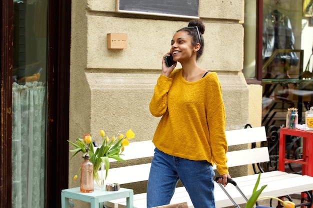 Femme souriante voyageant avec sac et téléphone portable