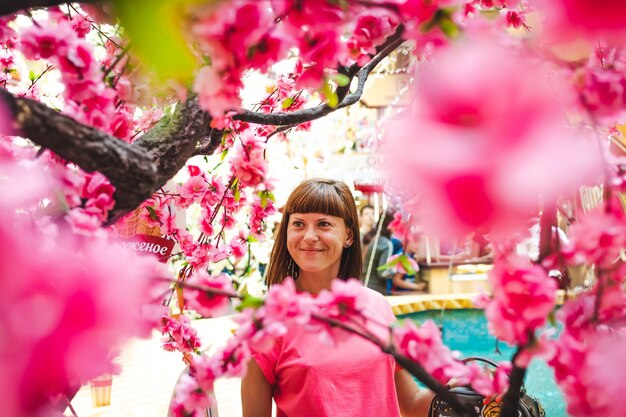 Photo une femme souriante vue à travers une plante à fleurs roses