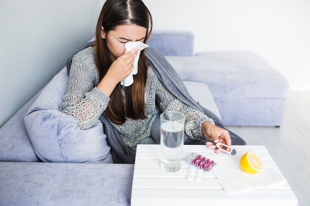 Femme sous couverture avec des médicaments