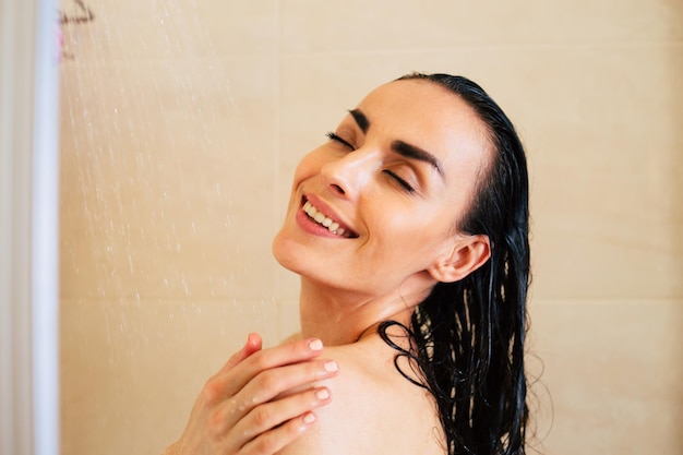 Femme sous la douche Belle fille souriante se prépare à prendre une douche