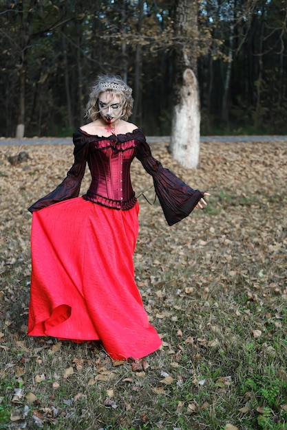 Une femme sous la forme d'un vampire ou d'une sorcière dans un corset et une longue jupe rouge