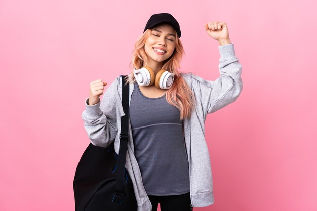 Femme de sport adolescent avec sac de sport sur fond isolé célébrant une victoire