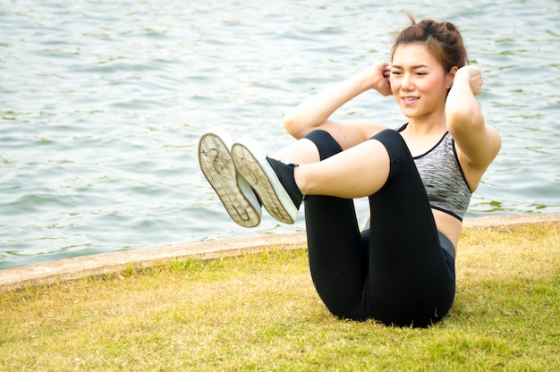 Photo femme de sport asiatique se réchauffer pour exercer sur les pelouses vertes