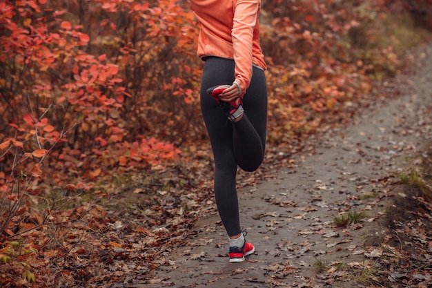 Femme de sport fatigué en vêtements de sport dans la forêt d'automne