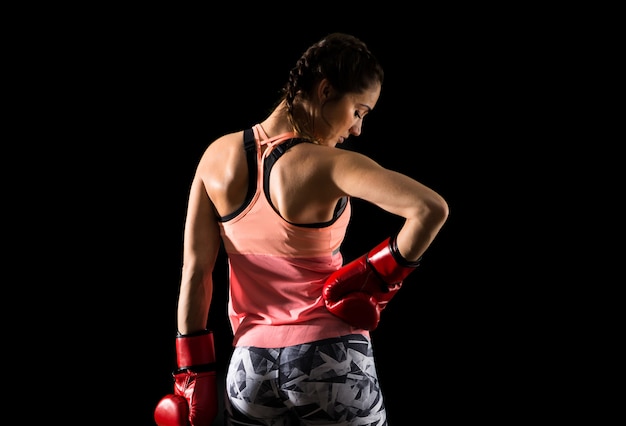 Femme de sport sur fond sombre avec des gants de boxe