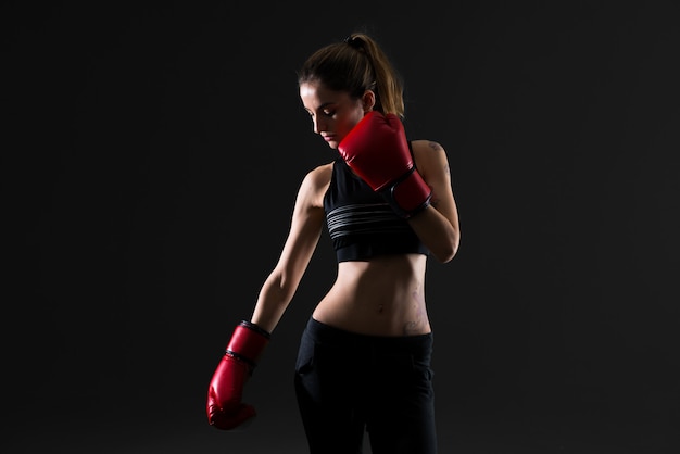 Femme de sport avec des gants de boxe sur fond sombre