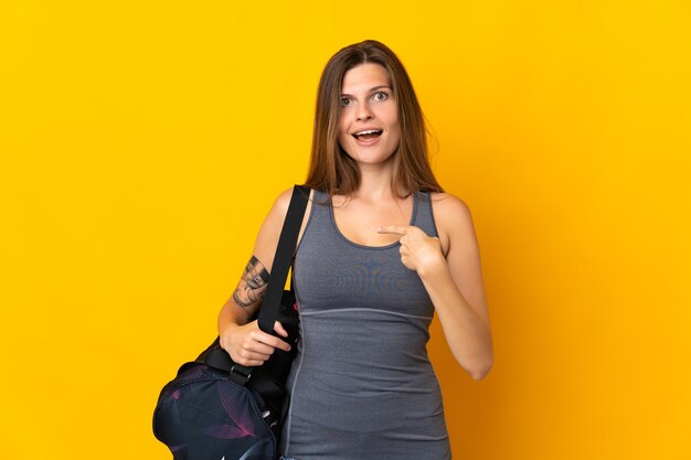 Femme de sport slovaque avec sac de sport isolé sur fond jaune avec une expression faciale surprise