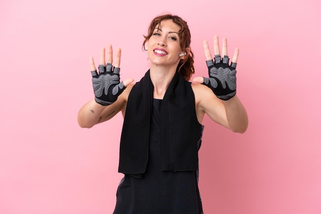 Femme de sport sport avec une serviette isolée sur fond rose comptant dix avec les doigts