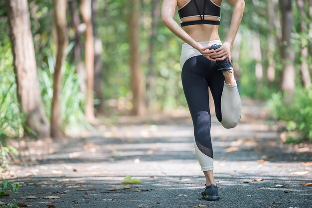 Femme sportive asiatique qui s'étend du corps respirant de l'air frais dans le parcThailand peopleConcept de remise en forme et d'exerciceJogging dans le parc