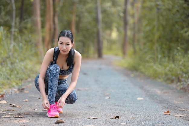 Femme sportive asiatique qui s'étend du corps en respirant de l'air frais dans le parcThaïlandaisConcept de remise en forme et d'exerciceJogging dans le parc